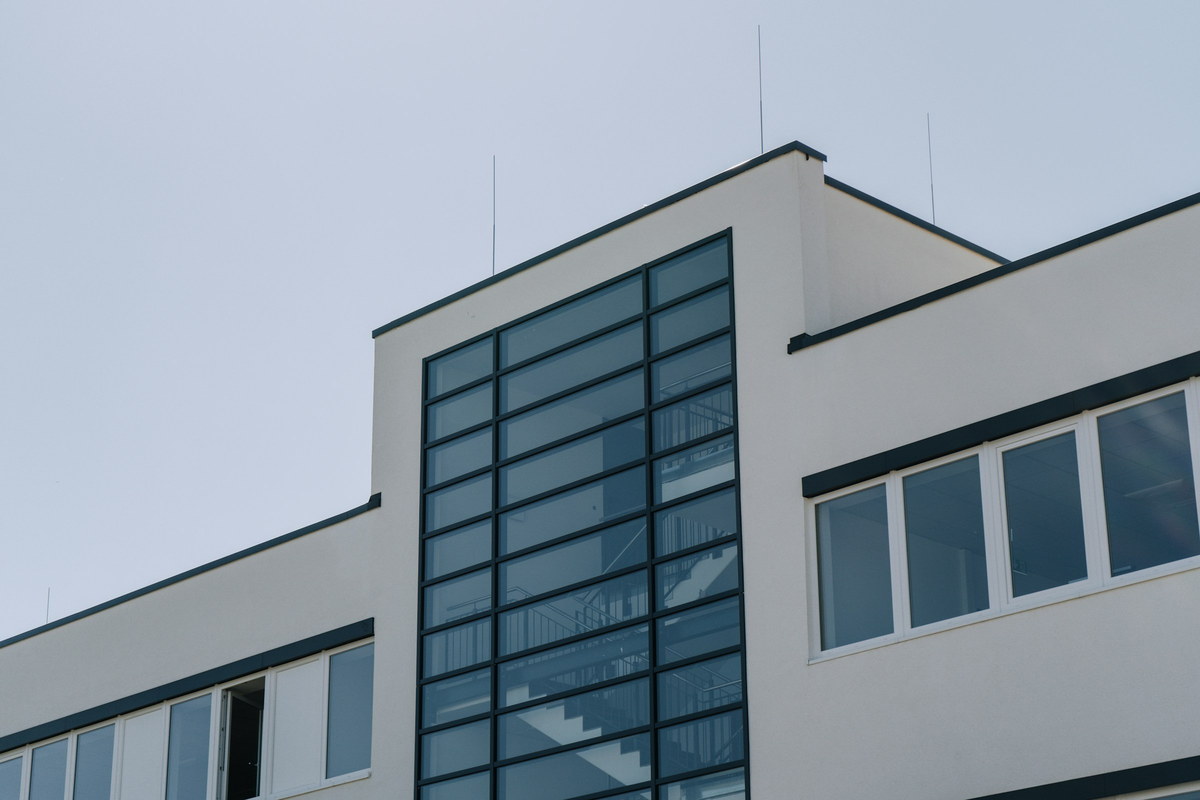 The upper floors of a light industrial building, with a glazed
                    stair tower against a pale sky.