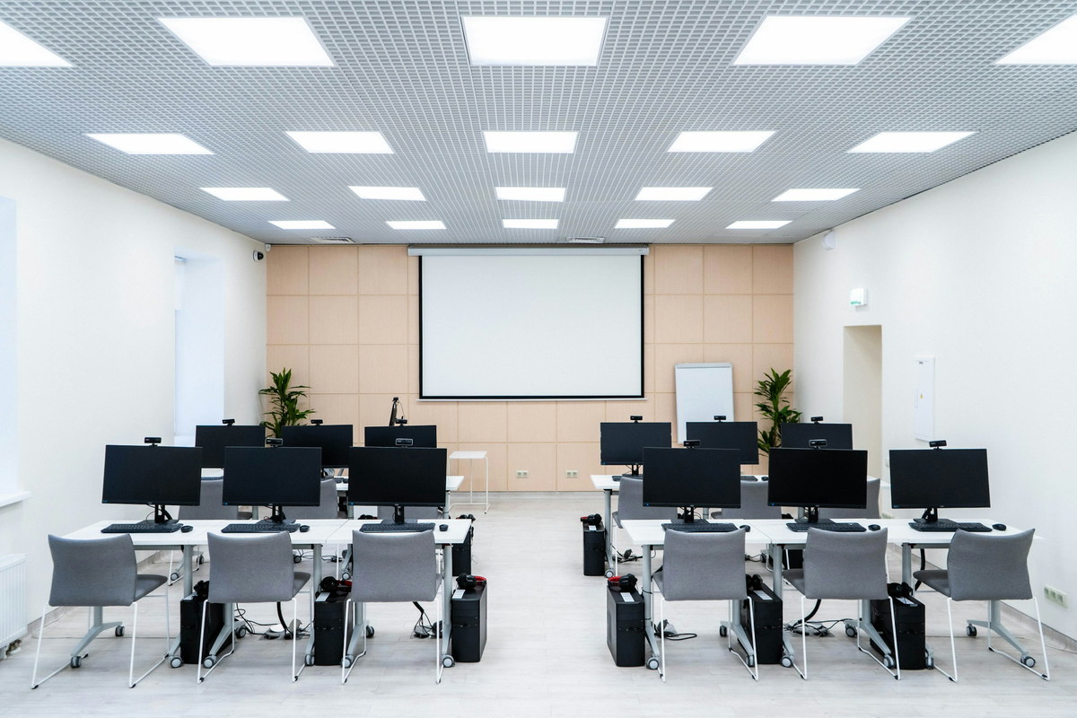 An examination room: rows of desks with monitors and keyboards
                      facing a projection screen.