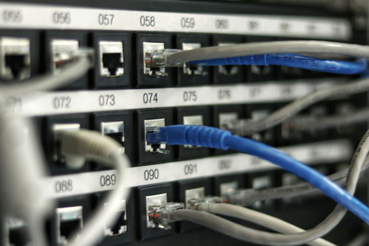 A numbered patch panel with blue and grey patch leads run between ports.